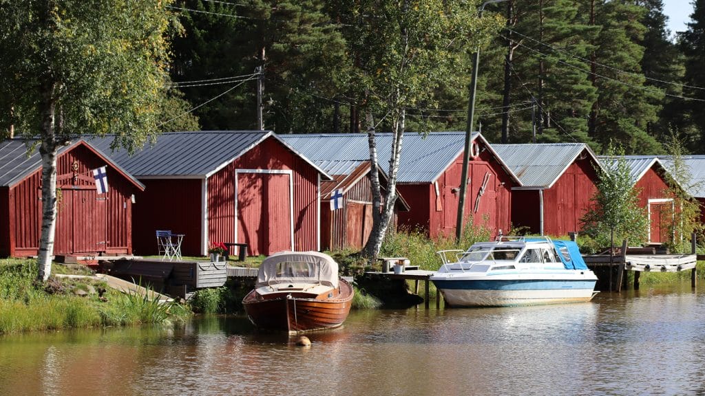 Sunti ja sen takana olevia punaisia venevajoja. Venevajojen edessä on kaksi laituriin kiinnitettyä venettä.