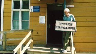 Veikko Salkio håller Pummanki naturskyddsområdets skylt framför Kieppi i början på 2000-talet.