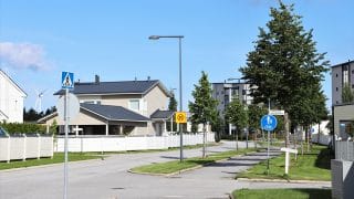 Näkymä Meripuiston asuinalueelle. Keskellä kuvaa kulkee alueelle vievä asfaltoitu tie sekä pyörätie, joiden varrella kasvaa pieniä lehtipuita. Etualalla olevien puiden, valaisinpylväiden ja liikennemerkkien takana on aidattuja omakotitalojen tontteja. Kauempana näkyy myös kerrostalo. Kuvan vasemmassa laidassa, kahden omakotitalon välistä näkyy myös kaukana oleva tuulimylly.