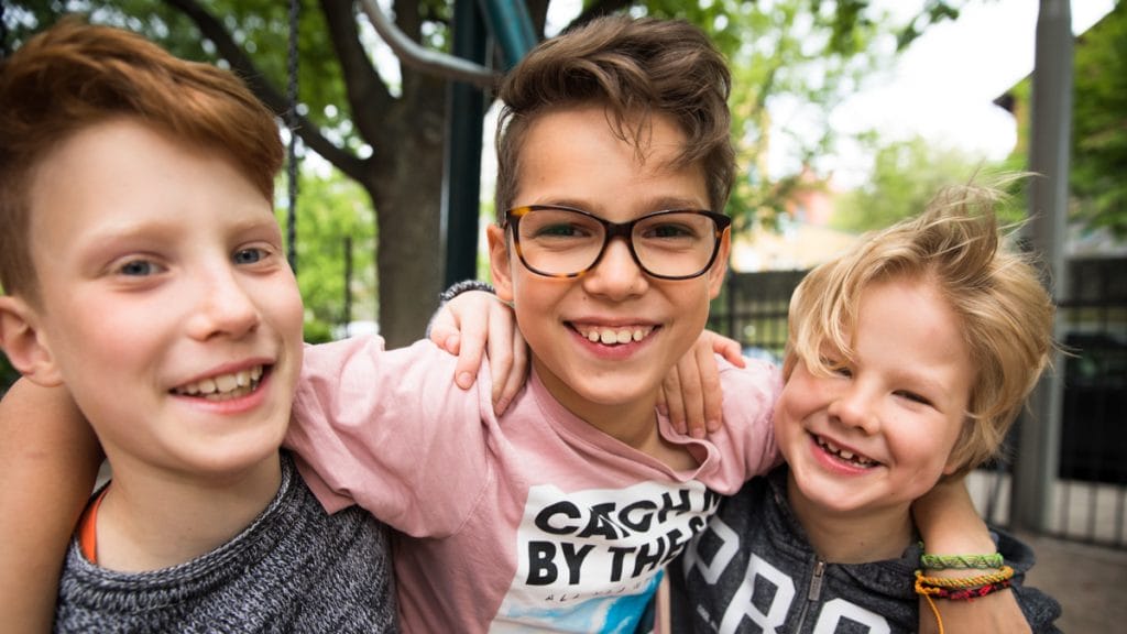 Three pupils smiling outside.