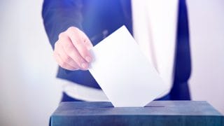 Käsi pudottaa äänestyslipúkkeen uurnaan