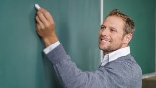 Opettaja kirjoittaa liitutaululle