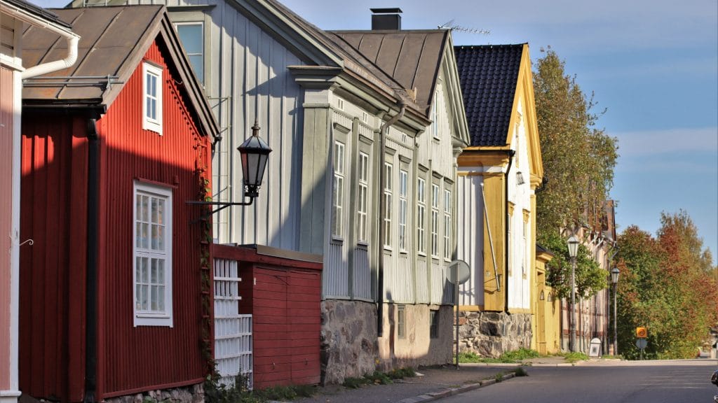 Kesäinen katunäkymä Neristanista. Kuvan vasemmassa reunassa on vanhoja puutaloja, lähimpänä punainen harjakattoinen talo, jossa valkoiset ikkunanpielet. Talon seinästä lähtee metallinen varsi, jonka päässä on vanha katulyhty. Talojen edessä kulkee asfaltoitu katu.