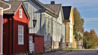 Kesäinen katunäkymä Neristanista. Kuvan vasemmassa reunassa on vanhoja puutaloja, lähimpänä punainen harjakattoinen talo, jossa valkoiset ikkunanpielet. Talon seinästä lähtee metallinen varsi, jonka päässä on vanha katulyhty. Talojen edessä kulkee asfaltoitu katu.