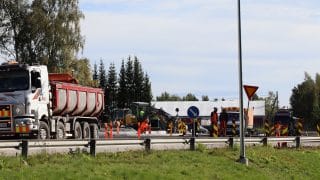 Halkokarin liikenneympyrän rakennustyömaa kesällä. Kuvan vasemmassa laidassa on tien varteen pysäköity kuorma-auto ja sen takana työmaa, jossa työntekijöitä ja työntekoon tarvittavaa kalustoa.