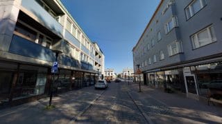 Näkymä Isokadulta, jossa molemmilla puolin katua matalia kerrostaloja. Kerrostalojen katutasossa on liiketiloja ja ylemmissä kerroksissa asuntoja. Kadun keskiosa on tehty mukulakivistä ja sen reunamilla on pysäköintipaikkoja kadun molemmin puolin. Taustalla etäisenä näkyy Mannerheiminaukio.
