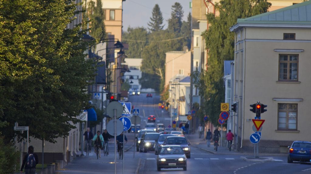 Katunäkymä Torikadulta. Kadun molemmin puolin on korkeita rakennuksia ja kadulla paljon autoja sekä pyöräilijöitä.