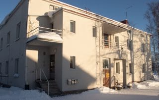Aurinko paistaa talvella valkoiseen kaksikerroksiseen kivirakennukseen.