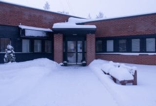 Punatiilisen rakennuksen sisäänkäynti talvella.