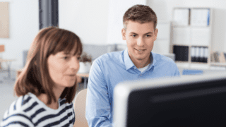 A women and a man are looking at a computer screen.